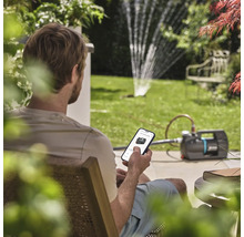 Muž ovláda záhradné čerpadlo pomocou aplikácie pre smartfóny v záhrade