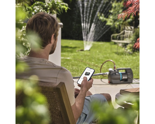 Muž ovláda záhradné čerpadlo pomocou aplikácie pre smartfóny v záhrade