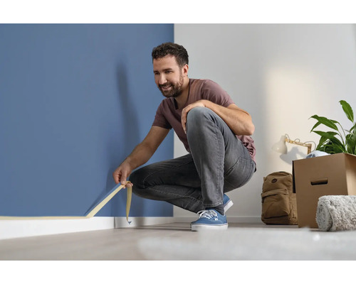 Muž lepí maskovaciu pásku na stenu