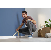 Muž lepí maliarsku pásku na stenu pre maliarske práce