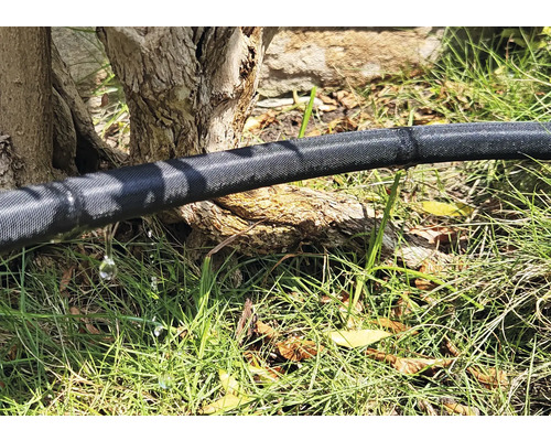 Zavlažovacia hadica v záhrade s unikajúcou vodou