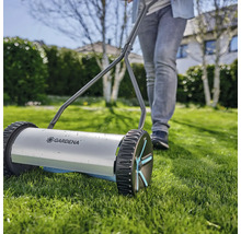 Ručná kosačka na trávu s osobou v záhrade.