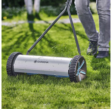 Ručná kosačka na trávu pri práci na trávniku s logom Gardena