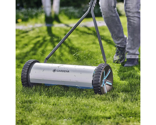 Ručná kosačka na trávu pri práci na trávniku s logom Gardena