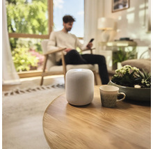 Zariadenie obývacej izby s inteligentným reproduktorom na stole.