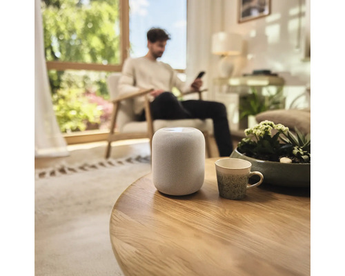 Zariadenie obývacej izby s inteligentným reproduktorom na stole.