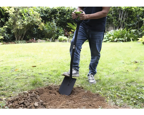 Osoba používa rýľ v záhrade na vykopávanie zeminy.