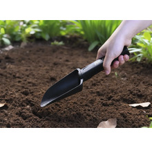 Osoba používa ručnú lopatku v záhrade.