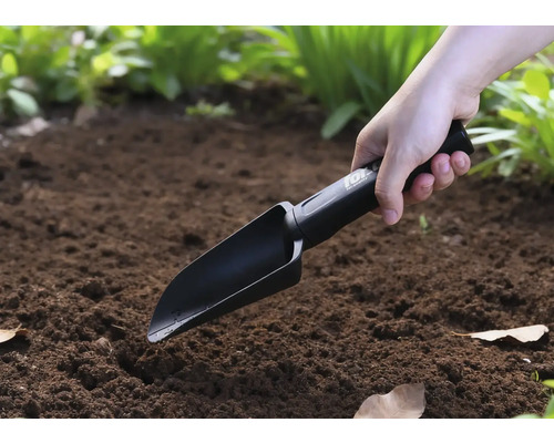 Osoba používa ručnú lopatku v záhrade.