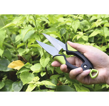 Ruka so záhradníckymi nožnicami pred zelenými rastlinami