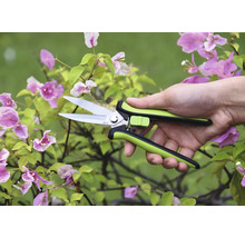 Záhradné nožnice v ruke pred kvitnúcou rastlinou