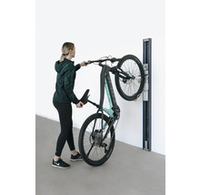 Žena zavesuje elektrický horský bicykel na nástenný držiak.