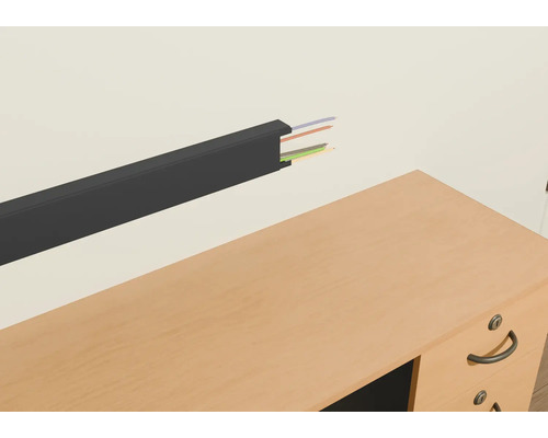 Plastový káblový kanál s káblami na stene nad stolom