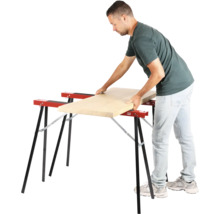 Muž pokladá drevenú dosku na dve kozy