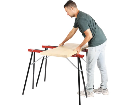 Muž pokladá drevenú dosku na dve kozy