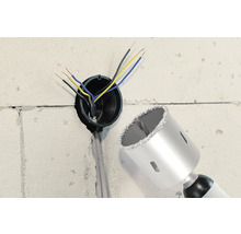 Stena s vyvŕtaným otvorom, elektrickými káblami a korunkovým vrtákom.