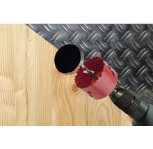 Dierovacia píla vŕta otvor do dreva s ryhovaným plechom v pozadí