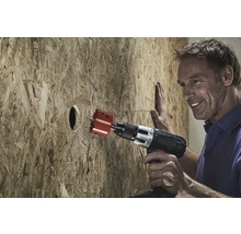 Muž vŕta otvor do drevenej dosky pomocou dierovacej píly