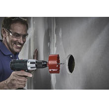 Muž vŕta do steny dierovkou.