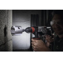 Muž vŕta dierovou pílou otvor do steny.