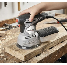 Ruka ovláda excentrickú brúsku Pattfield na drevenej doske.