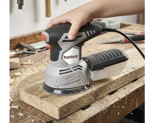 Ruka ovláda excentrickú brúsku Pattfield na drevenej doske.