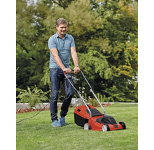 Muž kosí trávnik elektrickou kosačkou.