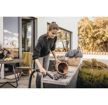 Žena čistí terasu vysávačom vedľa kvetináča