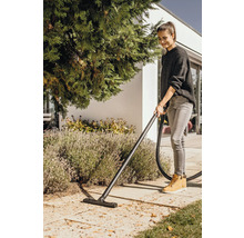 Žena vysáva lístie v záhrade pomocou mokrého a suchého vysávača