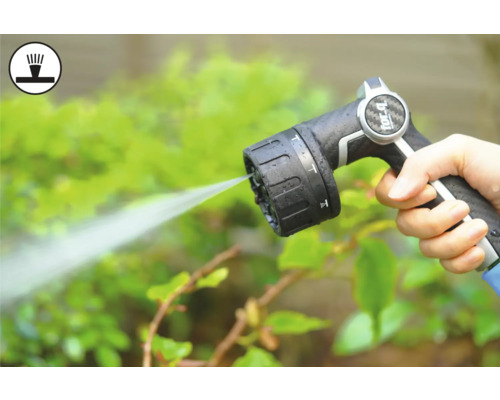 Ruka drží striekaciu pištoľ záhradnej hadice pri zalievaní rastlín