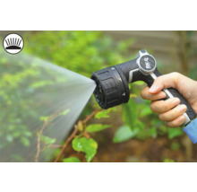 Ruka drží záhradnú striekaciu pištoľ, ktorá strieka vodu