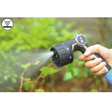 Ruka drží záhradnú striekaciu pištoľ s prúdom vody