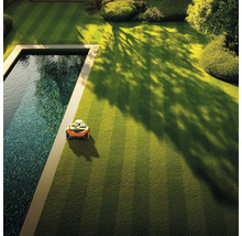 Robotická kosačka na trávniku vedľa bazéna