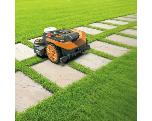Robotická kosačka na trávniku s cestou z kamenných dosiek