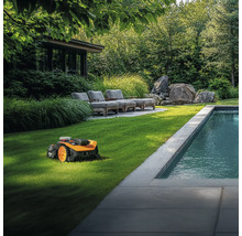 Robotická kosačka v prevádzke na trávniku vedľa bazéna