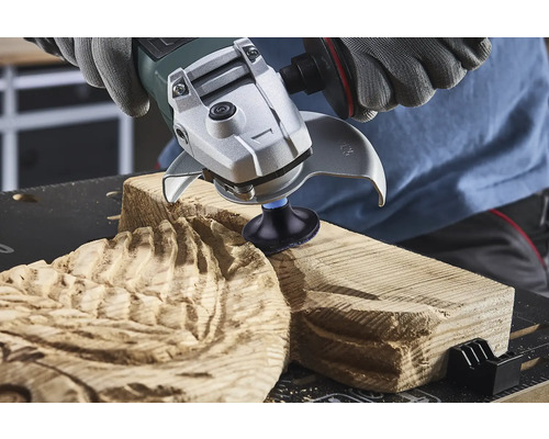 Osoba používa uhlovú brúsku na opracovanie dreva.