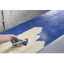 Osoba používa rozmetadlo farieb na nanášanie farby na drevo