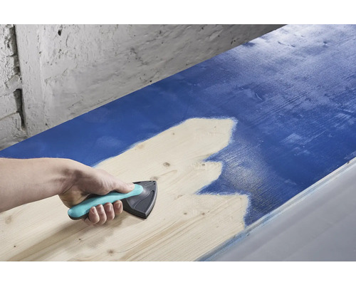 Osoba používa rozmetadlo farieb na nanášanie farby na drevo