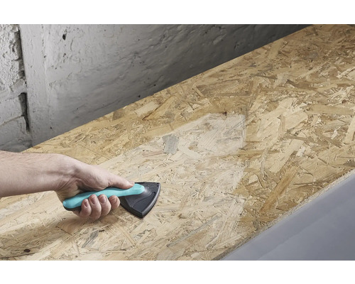 Ruka drží brúsny blok a brúsi drevenú dosku.