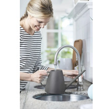 Žena plní sivú kanvicu na polievanie pri vodovodnom kohútiku