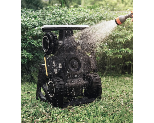 Zavlažovaný záhradný robot s pásovým pohonom v prevádzke na trávniku.
