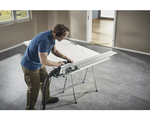 Remeselník reže dvere ručnou okružnou pílou na pracovnom stole.