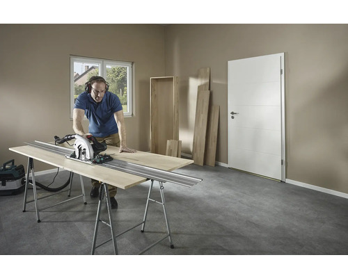 Muž reže drevo ručnou kotúčovou pílou na ponku v miestnosti.