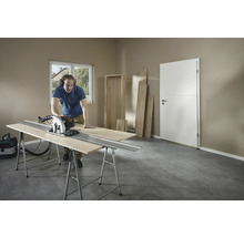 Muž reže drevo ručnou kotúčovou pílou na ponku v miestnosti.