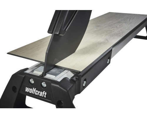 Rezačka na laminát Wolfcraft reže laminátovú dosku s dekórom dreva. Detailný pohľad na rezný mechanizmus.