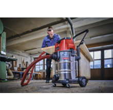 Dielňa s mokro-suchým vysávačom Einhell a mužom opracovávajúcim drevenú dosku