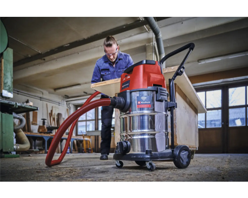 Dielňa s mokro-suchým vysávačom Einhell a mužom opracovávajúcim drevenú dosku