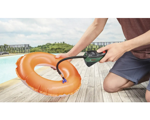 Osoba nafukuje plavecký kruh pomocou vzduchovej pumpy Bosch vedľa bazéna.