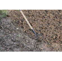 Trojzubý záhradný kultivátor s drevenou rukoväťou v záhradnej pôde