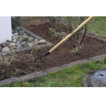 Záhradná scéna s kultivátorom s drevenou rukoväťou pri obrábaní pôdy